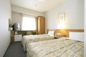 um quarto de hotel com duas camas e uma televisão em Hotel Route-Inn Osaka Honmachi em Osaka