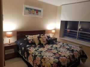a bedroom with a bed with a floral bedspread and two lamps at Laguna Bahía, Algarrobo in Algarrobo
