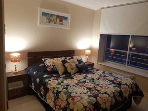 a bedroom with a bed with a floral bedspread and two lamps at Laguna Bahía, Algarrobo in Algarrobo +18 photos