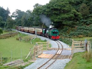a steam train traveling down the tracks in a field at Ystumgwern Luxury Barn Conversions in Dyffryn