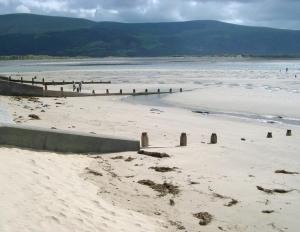 a beach with people walking on the sand at Ystumgwern Luxury Barn Conversions in Dyffryn