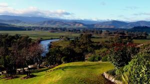 a river in a field with mountains in the background at Snowy Mountain Holidays in Towong