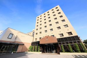 a large white building with windows on a street at Maple Inn Makuhari in Chiba