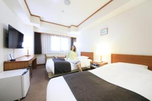 a woman sitting on a bed in a hotel room at Maple Inn Makuhari in Chiba +13 photos