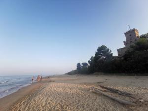 people walking on the beach with a castle in the background at Residenza Sant'Angelo Appartamento ampio con Giardino vicino al Mare in Citta' Sant'Angelo