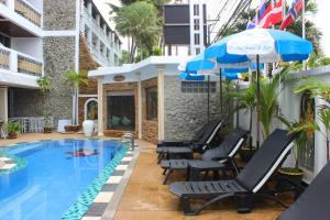 ein Pool mit Stühlen und Sonnenschirmen neben einem Gebäude in der Unterkunft Orchid Hotel and Spa Kalim Bay in Patong Beach
