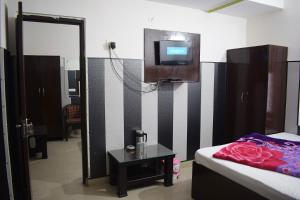Habitación con cama y TV en la pared. en Hotel Thakur Ji, en Haridwar