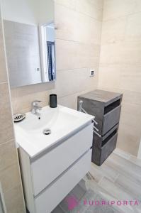 Un baño con un lavabo blanco y un espejo. en Residenza Bolzoni Avio, en Parma