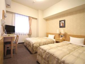 a hotel room with two beds and a desk with a computer at Hotel Route-Inn Nahatomariko in Naha