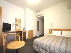 um quarto de hotel com uma cama, uma mesa e uma secretária em Hotel Route-Inn Nahatomariko em Naha