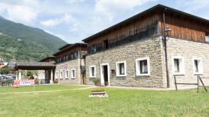 ein großes Steingebäude mit einem Grasfeld davor in der Unterkunft Due Parchi B&B in Vezza dʼOglio