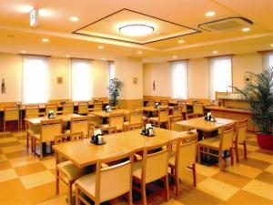 a restaurant with wooden tables and chairs and windows at Hotel Route-Inn Niigata Kencho-minami in Niigata