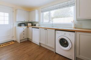 a white kitchen with a washer and dryer in it at Sunset in Newquay