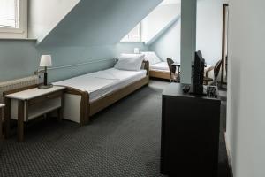 a room with a bed and a desk and a tv at Hotel Carlstadt in Karlovac