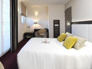 a bedroom with a large white bed with yellow pillows at Hôtel Restaurant Les Grains d'Argent Dizy - Epernay in Épernay