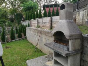 a stone oven in a garden with a wall at Apartment House Papa in Vinica