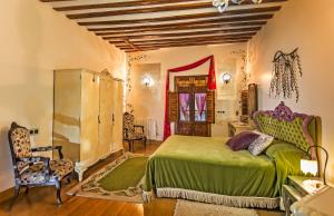 1 dormitorio con cama verde, mesa y sillas en Casa Palacio Rincón de la Catedral, en Toledo