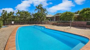 una piscina azul frente a una valla en River Gum Luxury Bed and Breakfast, en Diddillibah