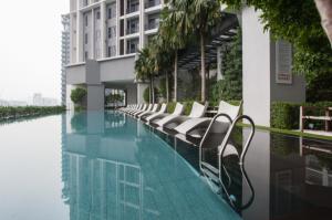 a swimming pool with white chairs next to a building at KLCC The Mews Home in Kuala Lumpur