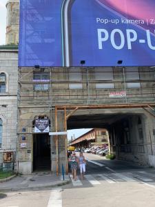 dos personas de pie bajo un cartel de pop up en un edificio en Rirooms, en Rijeka
