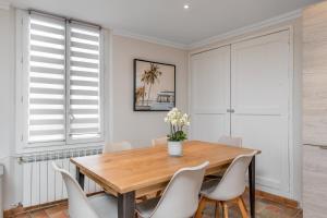 a dining room with a wooden table and white chairs at My rima in Antibes