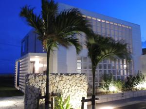 a hotel with palm trees in front of a building at Umi no Yado Umikaze in Henza