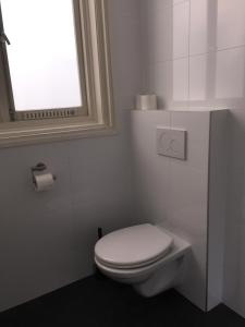 a white bathroom with a toilet and a window at Bnbrose in Amsterdam