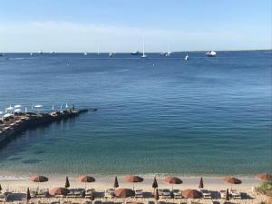 uma praia com guarda-sóis e barcos na água em Rives d'Or em Antibes