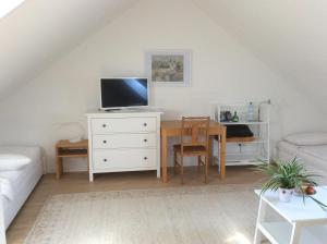 a living room with a desk with a tv and a table at Haus am Wald in Waldbrunn