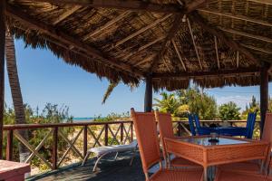 a table and chairs on a deck with the beach at Pousada e Restaurante Tremembé in Icapuí