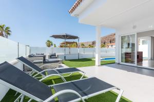 a patio with lawn chairs and an umbrella at Luxurious 5* VILLA - 300M2 - private HEATED pool - garage - WiFi in Palm-mar