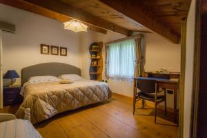 sypialnia z łóżkiem i biurkiem obok okna w obiekcie La Tinaia Country House w mieście Magomadas