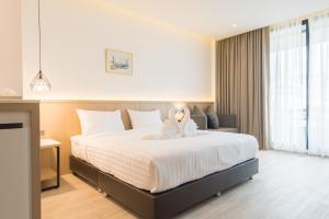 um quarto com uma cama grande e um urso de peluche. em Madison Bangkok Hotel em Bangkok