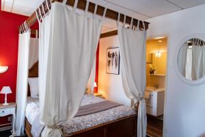 Un dormitorio con una cama con dosel y cortinas blancas. en Hotel Henri IV, en Sully-sur-Loire