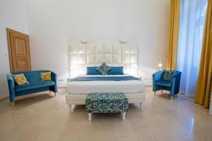 a bedroom with a bed and two blue chairs at Duke's Residence in Budapest