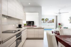 a kitchen with white cabinets and a dining room at Luxurious 5* VILLA - 300M2 - private HEATED pool - garage - WiFi in Palm-mar