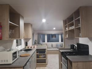 uma cozinha com um fogão e um sofá num quarto em Tattershall Lakes 2020 8 Berth Caravan With Hot Tub em Tattershall