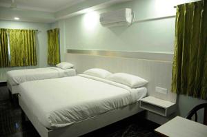 ムザッファルプルにあるHOTEL CENTRAL SQUARE "A Couple Friendly Hotel"のベッド2台とテーブルが備わるホテルルームです。