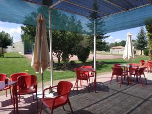 un patio con mesas, sillas y una sombrilla en Hostal restaurante la concordia, en Fuentes Claras