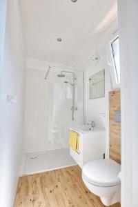 uma casa de banho branca com um WC e um chuveiro em Przyjazne domki em Lubogoszcz