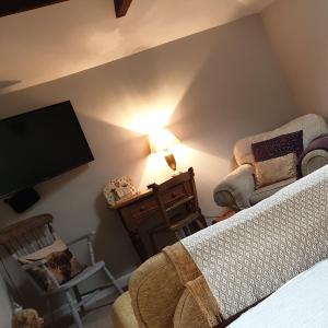 a bedroom with a bed and a chair and a tv at The Nest at Bramble Cottage Lacock in Lacock
