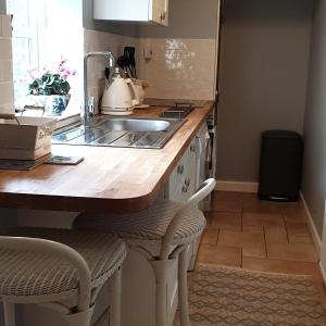 cocina con fregadero y encimera con 2 sillas en The Nest at Bramble Cottage Lacock en Lacock