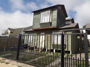 a house with a fence in front of it at Cabañas Antomai in Pichilemu