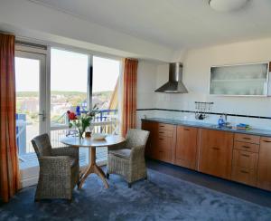 een keuken met een tafel en stoelen en een raam bij Appartementen de Strandloper in Bergen aan Zee