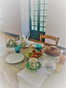 Una mesa con platos, tazas y fruta encima. en Maison du Moulin, en Donzy