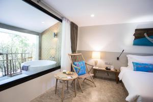 a bedroom with a tub and a bed and a chair at Deevana Krabi Resort in Ao Nang Beach