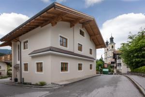 a white house with a wooden roof on a street at Haus Klingenschmid in Hopfgarten im Brixental