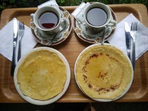 taca z dwoma talerzami naleśników i dwoma filiżankami kawy w obiekcie Purnama di Bisma w mieście Ubud