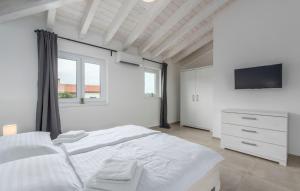 a white bedroom with a large bed and a tv at Villas Marisol in Premantura