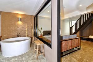 a bathroom with a white tub and a brick wall at Deevana Krabi Resort in Ao Nang Beach